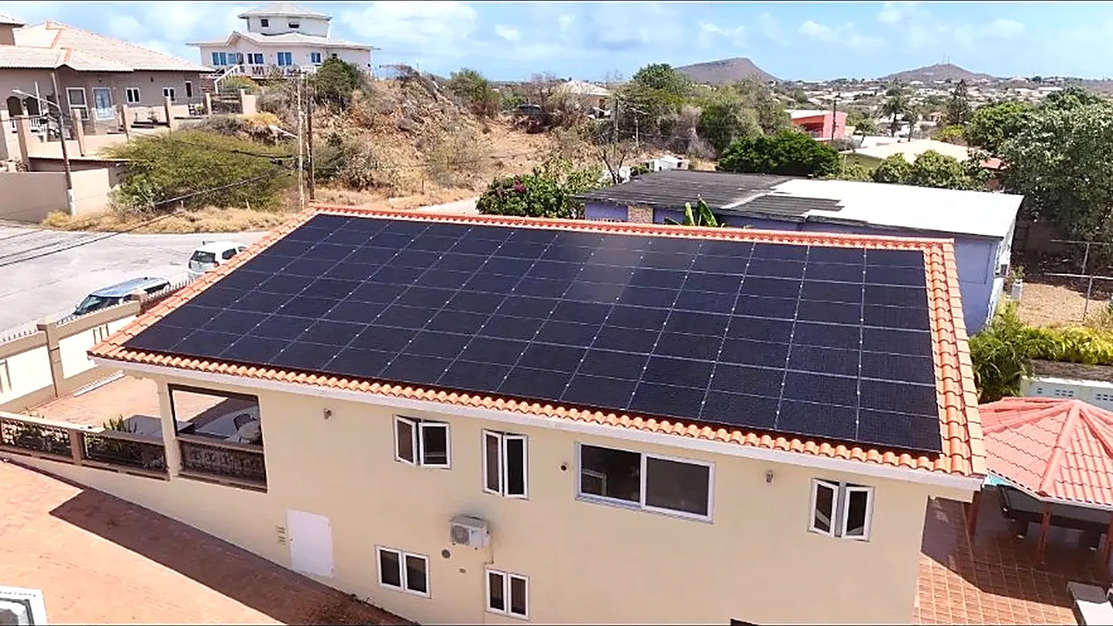 Volledig dak met zwarte zonnepanelen op een woning met rode dakpannen op Curaçao