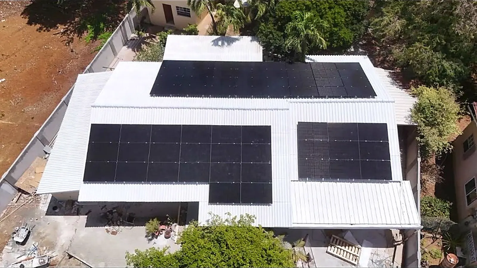 Zonnepanelen op een wit golfplaten dak van een bedrijfspand op Curaçao