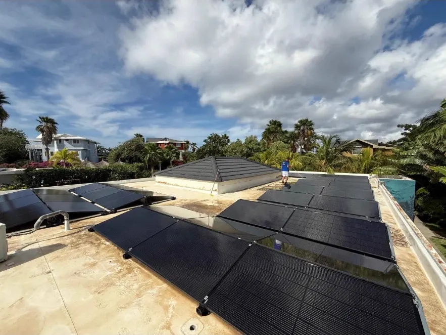 Full black zonnepanelen op een dak in Curaçao met palmbomen op de achtergrond